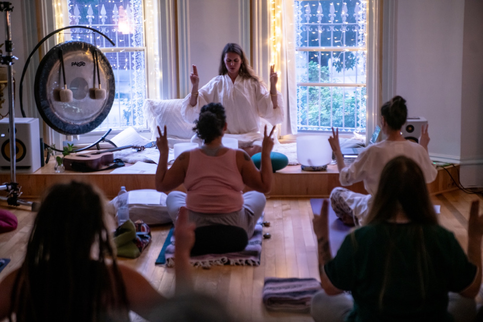 Hope Littwin leading a sound ceremony, gong and singing bowls, the room with hands raised